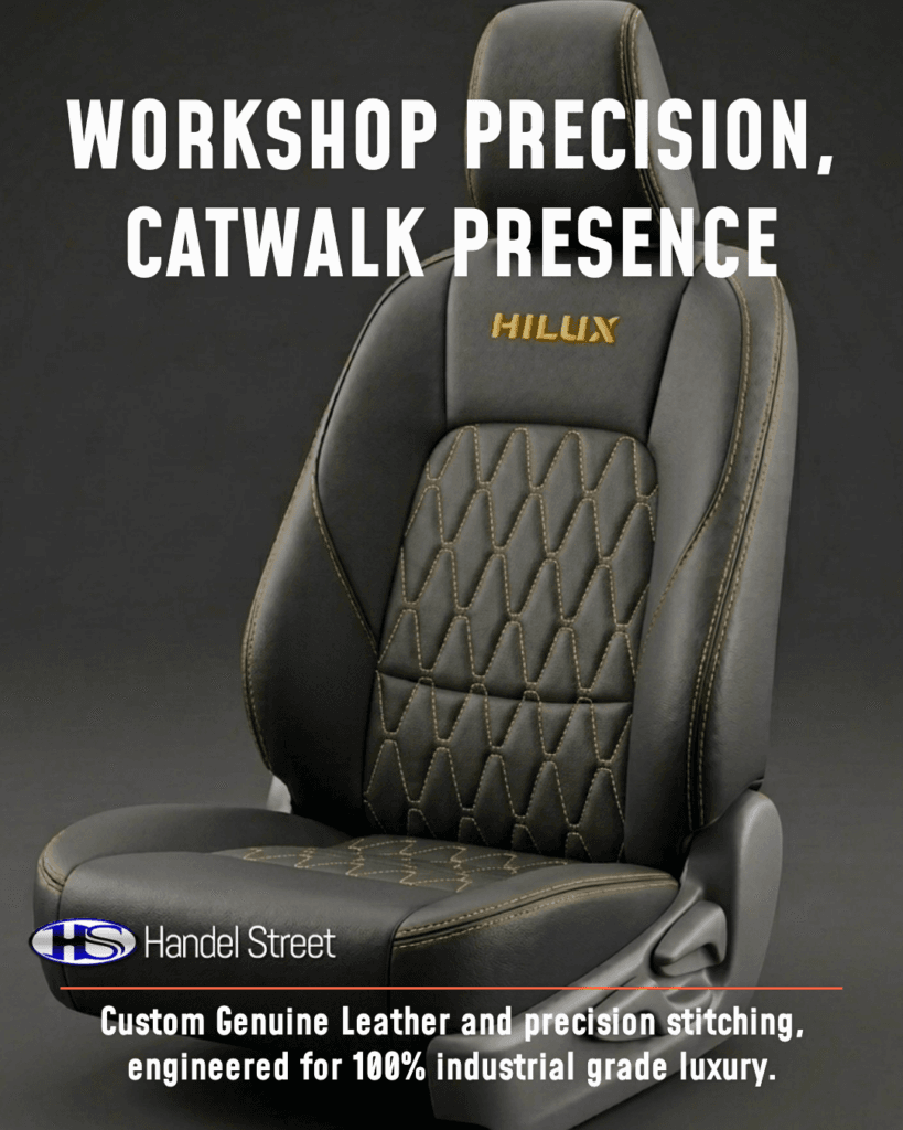 Three-quarter studio angle of a custom dark grey genuine leather car seat with gold contrast diamond quilting and "HILUX" embroidered in gold on the headrest.