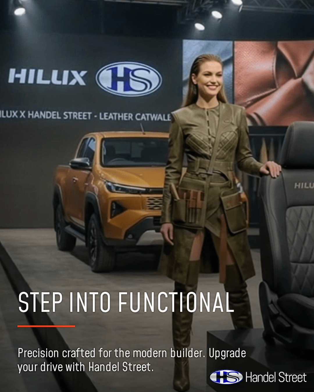 A fashion model in a tailored olive green leather outfit with a functional tool pouch stands on a runway next to a premium dark grey quilted leather seat and an orange Toyota Hilux bakkie.